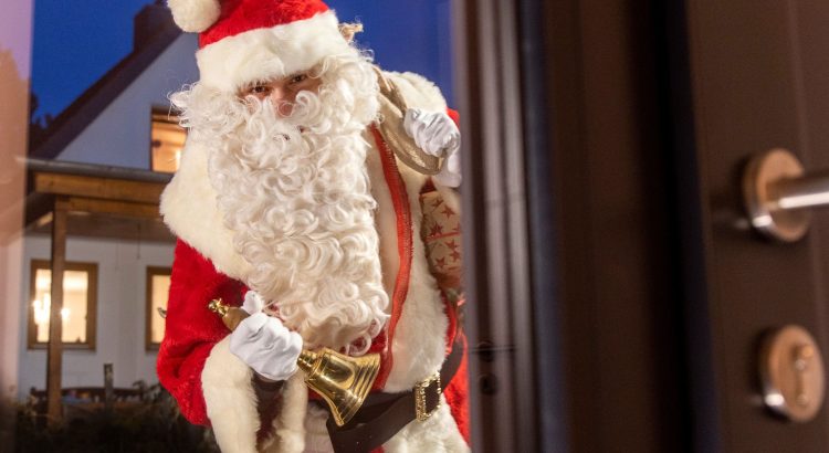 Weihnachtsmann vor festlich geschmücktem Haus